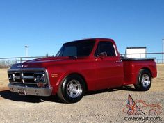 an old red pickup truck parked in the dirt