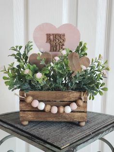 a wooden box with some plants in it and a heart shaped decoration on the top