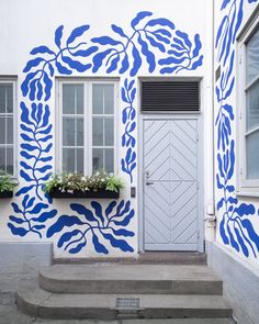 a blue and white painted building with flowers in the window boxes on the front door