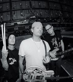 three men standing next to each other holding guitars