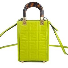 Introducing the Fendi FF Zucca Mini Sunshine Shopper Tote Crossbody Bag in 'Wasabi' Green Leather. This exquisite tote features the iconic Zucca print and is accentuated with gold-tone hardware. It offers versatility with rolled handles and a single adjustable shoulder strap, while the brown suede lining adds a luxurious touch. The open top design ensures easy access to your essentials while maintaining a sleek silhouette. Elevate your style with this timeless piece from Fendi. Model number 8BS0 Fendi Monster, Fendi Tote, Fendi Mini, Balenciaga Backpack, Small Leather Bag, Bag Green, Shopper Tote, Top Design, Shopper Bag