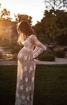 a woman standing in the grass with her back to the camera, wearing a white lace dress