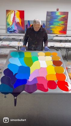 a man standing in front of a table with many different colors on it