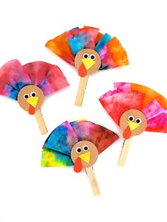 three paper turkeys on sticks made from colored tie - dyed material, each with a different face