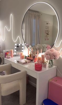 a white desk topped with a mirror next to a chair and table filled with candles