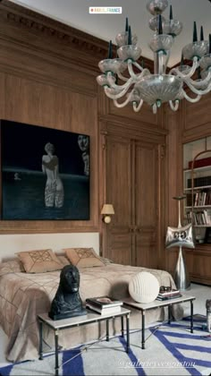 a bedroom with a chandelier hanging from the ceiling and a painting on the wall