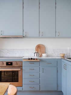 a kitchen with blue cabinets and white counter tops, an oven and microwave in the corner