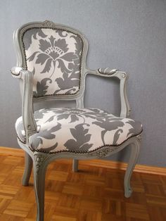 an old chair is upholstered against a wall with wood flooring and gray paint