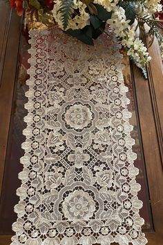 a vase filled with flowers sitting on top of a table next to a lace runner