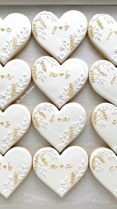 decorated cookies in the shape of hearts with gold writing on them are arranged in a box