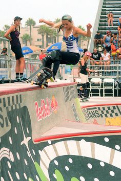 a woman riding a skateboard up the side of a ramp at a skate park