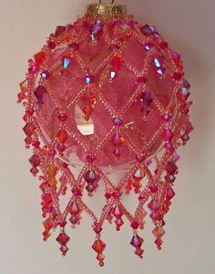 a pink ornament hanging from the ceiling on a white wall with beads and chains