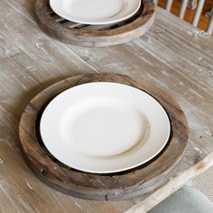 two white plates sitting on top of a wooden table next to each other with one empty plate in the middle