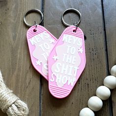 two pink keychains with words on them sitting next to twine of white beads