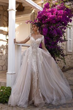 a woman in a wedding dress leaning against a pillar with purple flowers on the side