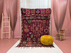 a room with pink walls and rugs on the floor next to a yellow chair