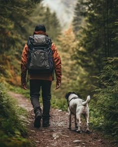 a man walking with his dog on a trail in the woods