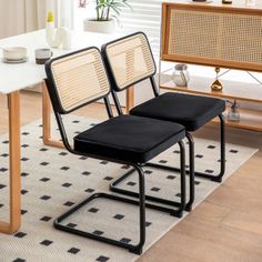 two black chairs sitting on top of a rug next to a white table and chair