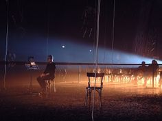 a group of people sitting around a fire pit in the middle of a dark room