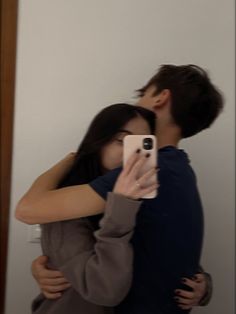 a man and woman taking a selfie in front of a mirror with their arms around each other