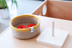 a basket with two red buttons in it on a table next to a pen holder