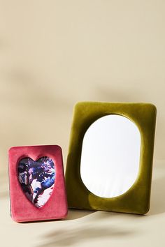 a heart shaped mirror sitting next to a green and pink box