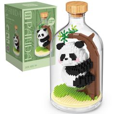 a glass bottle with a panda bear in it next to a cardboard box that is filled with legos