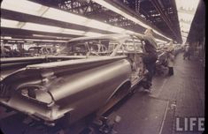 an assembly line with old cars being worked on in a factory or repair shop, and workers are working on the car