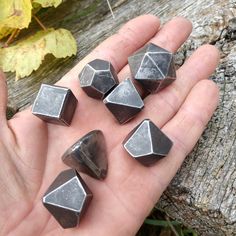 several pieces of metal sitting in the palm of someone's hand on a tree trunk