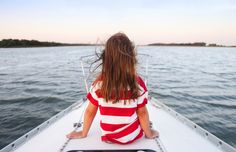 a woman sitting on the back of a boat looking out at the water stock photo