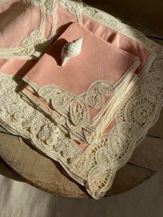 three pink and white lace napkins on top of a wooden table next to a spoon