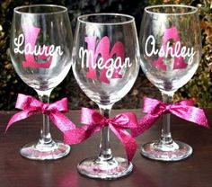 three wine glasses with pink bows are sitting next to each other on a wooden table