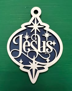 a metal ornament with the word jesus hanging from it's side on a green background