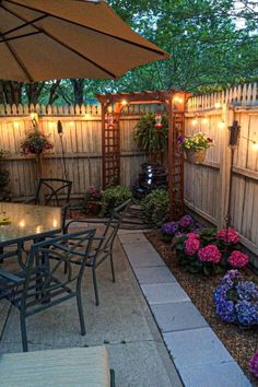 an outdoor dining area with patio furniture and lights on the fence, surrounded by flowers