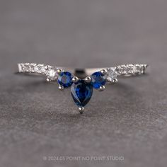 an engagement ring with two pear shaped blue sapphires and three diamonds on each side