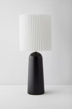 a black and white table lamp with a white shade on the top, against a white background