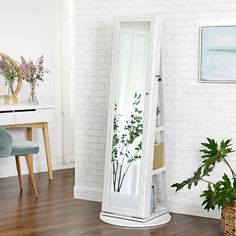 a white floor standing mirror next to a chair and potted plant in a living room