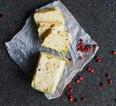 pieces of cheese sitting on top of a piece of wax paper next to some cranberries