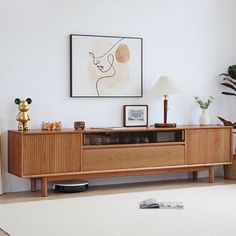 a living room with an entertainment center and pictures on the wall, plants in vases