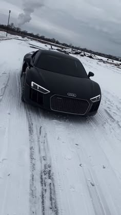 a black sports car driving down a snow covered road