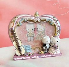 a hello kitty figurine set in a pink heart shaped frame with music instruments