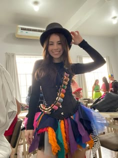 a woman in a black top and colorful skirt posing for the camera with her hands on her head