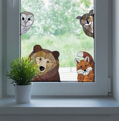 the window is decorated with three animals and a cat on it's side, as well as a potted plant