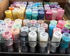 many different types of nail polish are on display in a store case with clear bins