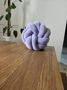 a purple knot sitting on top of a wooden table next to a potted plant