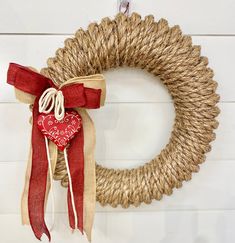 a red heart hanging on a rope wreath