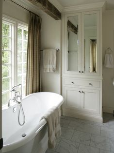 a white bath tub sitting in a bathroom next to a window