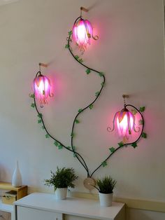 two pink lights are hanging on the wall next to a white table with potted plants