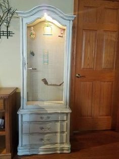 a white cabinet sitting in the corner of a room next to a wooden table and door