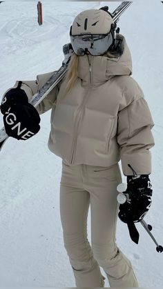 a woman standing on top of a snow covered slope holding skis